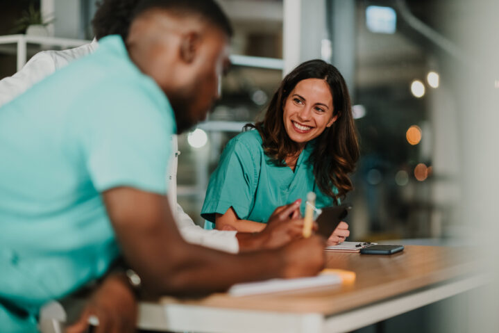 Healthcare professionals on night shift collaborating on medical records, smiling.