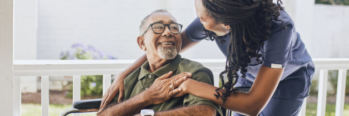 Young female nurse hugging an elderly man in a wheelchair